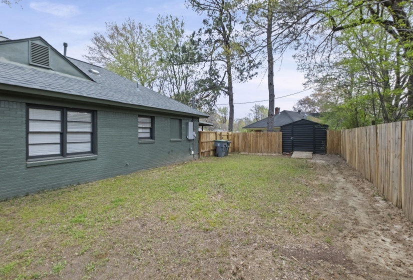 Fenced backyard featuring a storage shed