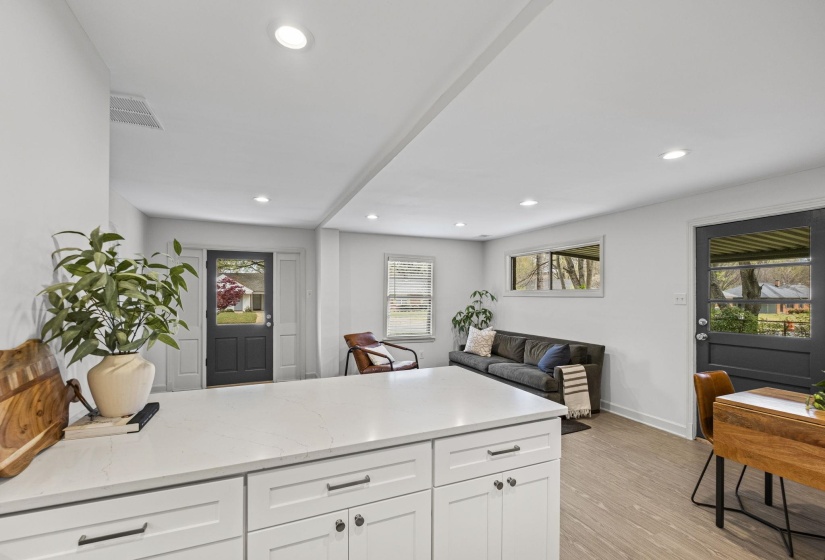 Kitchen with a peninsula, light stone countertops, white cabinets, open floor plan, and light wood-style floors