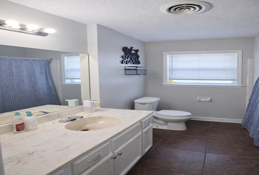 Bathroom featuring a shower with curtain, vanity, plenty of natural light, dark tile patterned floors, and a textured ceiling