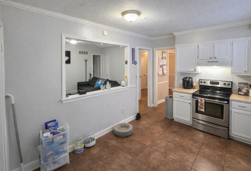 Kitchen featuring stainless steel electric stove, light countertops, white cabinetry, a textured ceiling, and crown molding