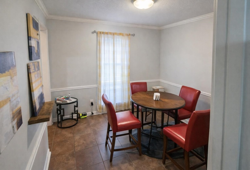 Dining space with crown molding, a textured ceiling, and dark tile patterned flooring