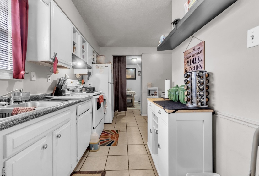 Kitchen with white cabinets, white electric stove, light tile patterned flooring, and open shelves
