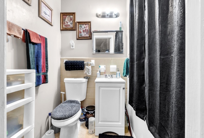 Full bath featuring vanity, tile walls, a wainscoted wall, tile patterned floors, and curtained shower