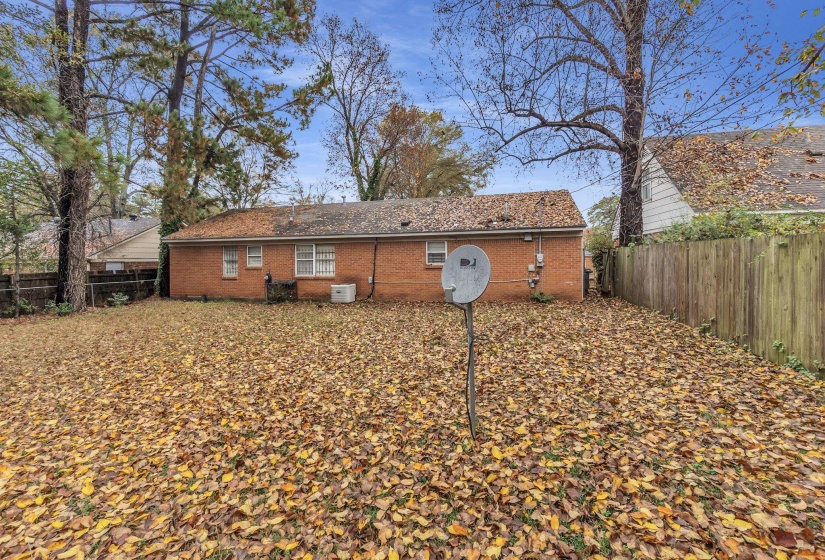 Back of property with a fenced backyard and brick siding
