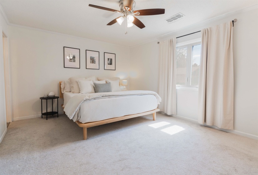 Bedroom with light carpet, ceiling fan, and ornamental molding