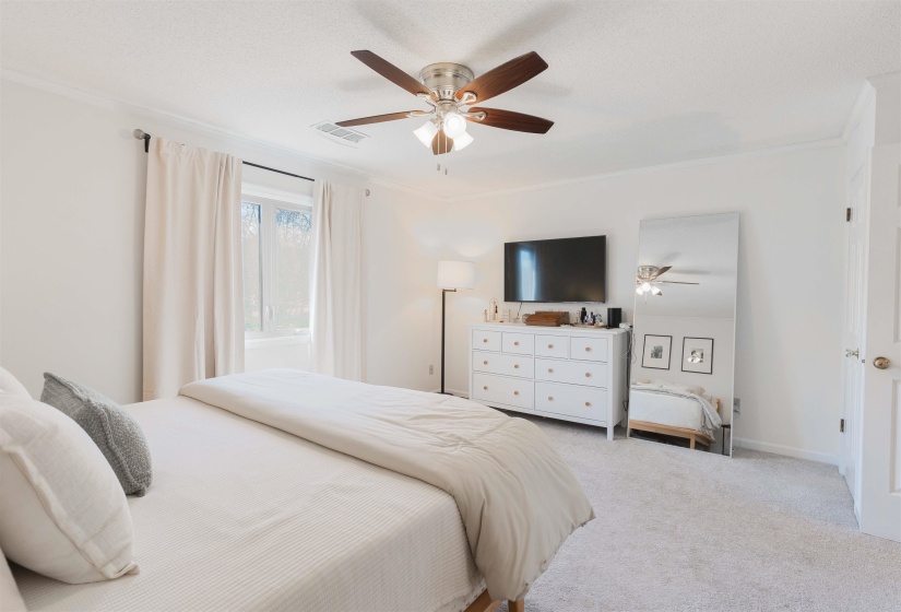 Bedroom with a ceiling fan, carpet, and ornamental molding