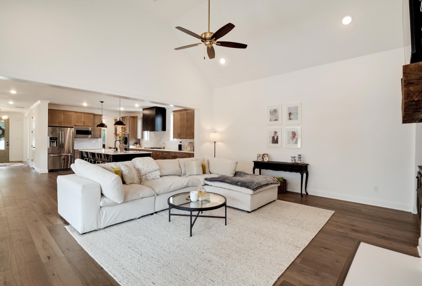 Living room with recessed lighting, ceiling fan, dark wood-type flooring, and lofted ceiling
