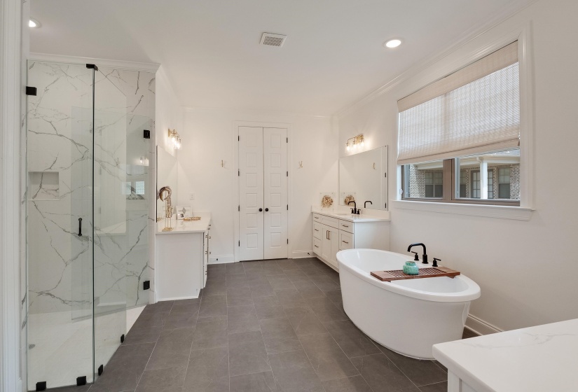 Bathroom featuring two vanities, recessed lighting, a marble finish shower, crown molding, and a soaking tub