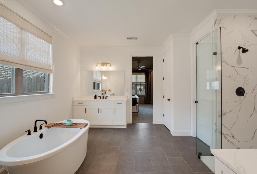 Ensuite bathroom with vanity, healthy amount of natural light, a marble finish shower, ornamental molding, and a ceiling fan
