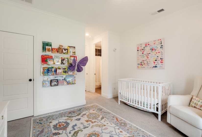 Bedroom with light carpet, crown molding, and a nursery area