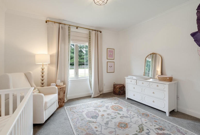 Bedroom featuring a nursery area, light carpet, and ornamental molding