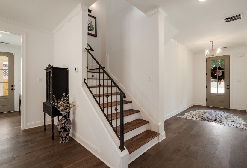 Foyer entrance with plenty of natural light, dark wood-type flooring, hanging lights, and crown molding