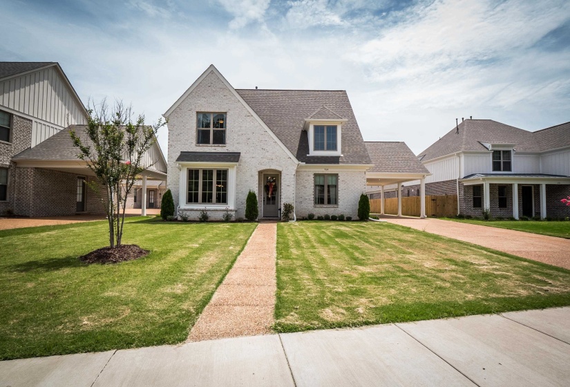 View of front of house with brick siding, a front yard, roof with shingles, concrete driveway, and an attached carport