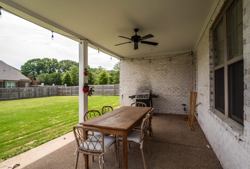 Fenced backyard with a patio, ceiling fan, outdoor dining area, and area for grilling
