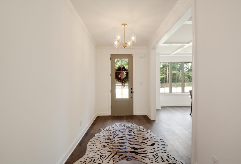 Foyer with dark wood finished floors, suspended lighting, and crown molding
