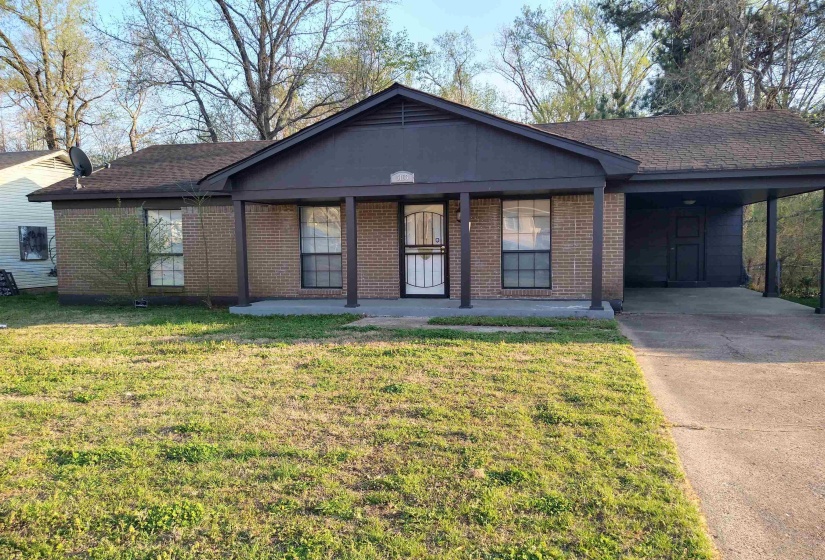 Ranch-style home featuring covered porch, a carport, brick siding, a front yard, and concrete driveway