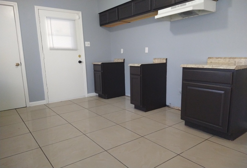Kitchen with under cabinet range hood and light tile patterned flooring