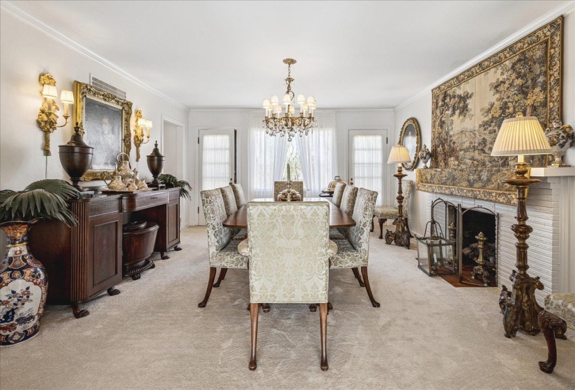 Dining room featuring light colored carpet, suspended lighting, ornamental molding, and a brick fireplace