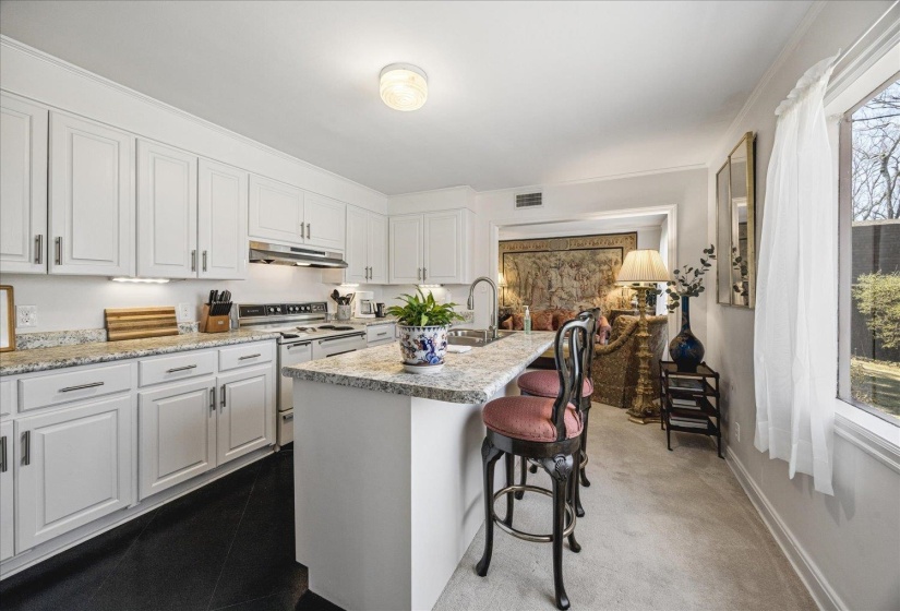 Kitchen featuring double oven range, white cabinetry, a kitchen island with sink, and a kitchen bar
