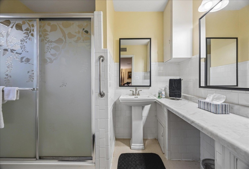Bathroom featuring a stall shower, tile walls, and wainscoting