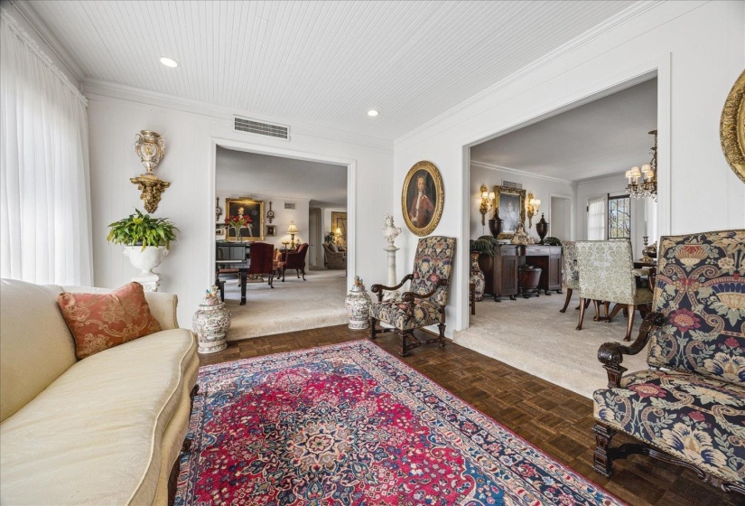 Living area with parquet flooring, ornamental molding, and hanging lights