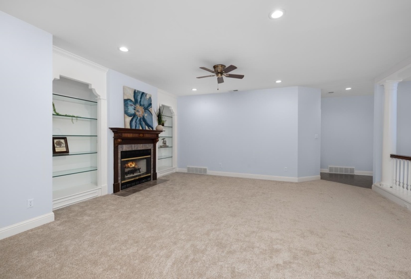 Unfurnished living room featuring ceiling fan, built in shelves, carpet flooring, recessed lighting, and a tiled fireplace