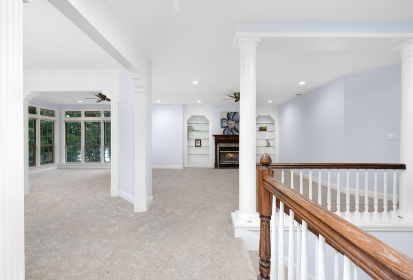 Hall with decorative columns, light carpet, recessed lighting, ornamental molding, and built in features