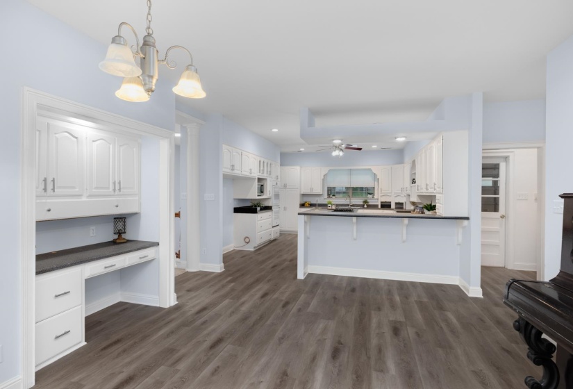 Kitchen with dark countertops, white cabinets, a peninsula, and a kitchen breakfast bar
