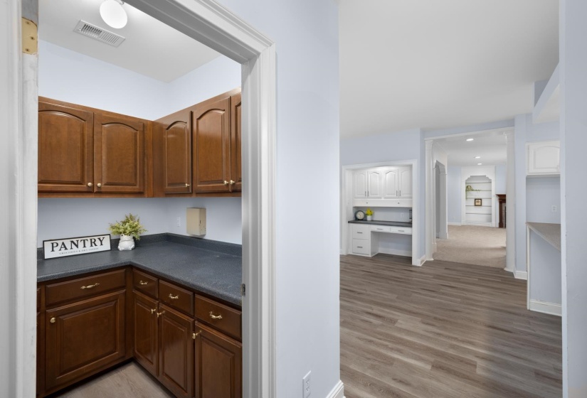 Bar featuring dark countertops, light wood finished floors, built in desk, and recessed lighting