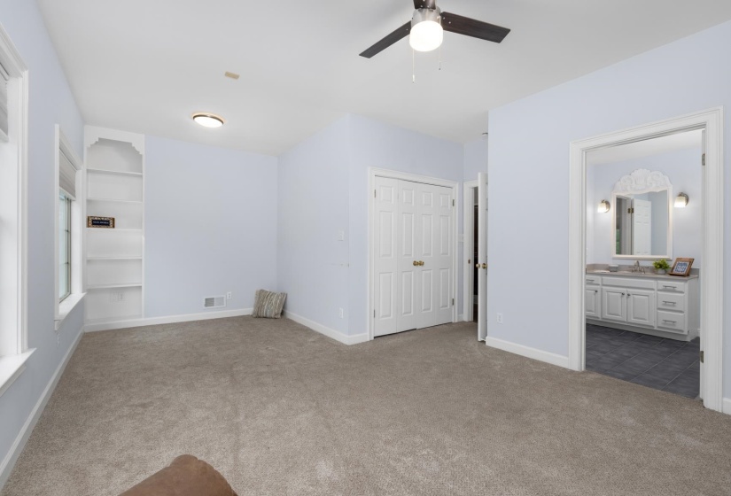 Unfurnished bedroom with carpet flooring, ceiling fan, and ensuite bath
