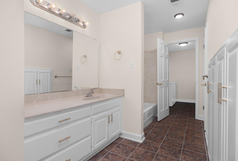 Bathroom with vanity, washtub / shower combination, dark tile patterned flooring, and a textured ceiling
