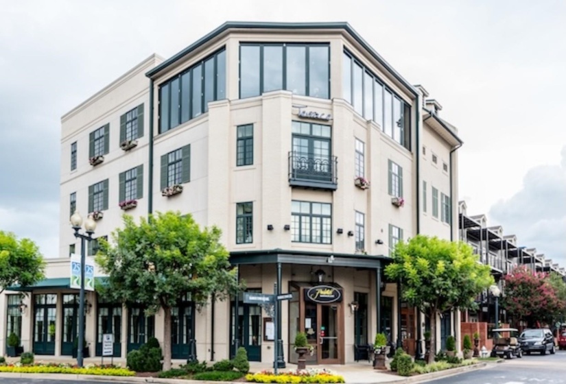 Cream brick building featuring prominent large-paned windows, dark contrasting shutters, and integrated window boxes