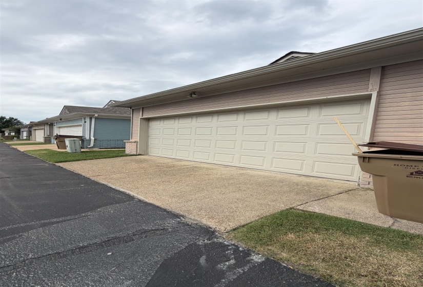 Attached garage with a panel-style door, concrete driveway, and neutral-toned siding