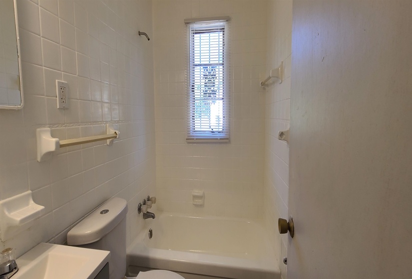 Full bathroom featuring vanity, tile walls, toilet, and washtub / shower combination