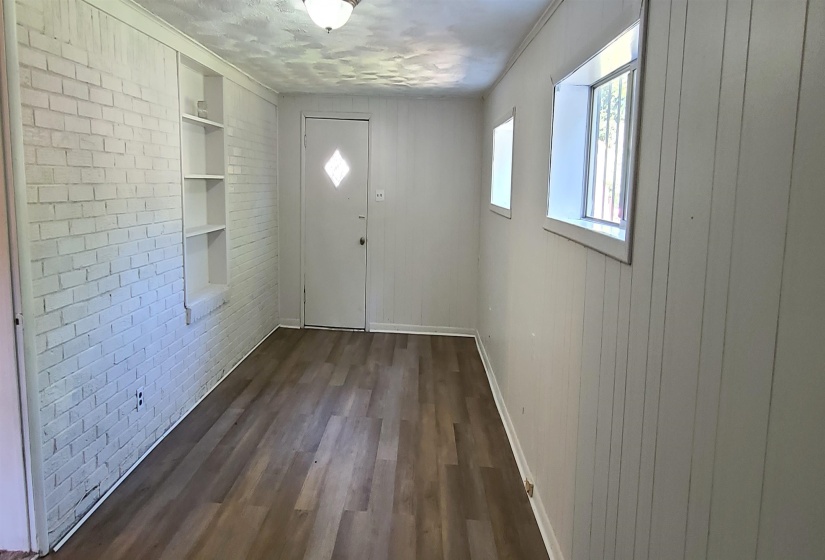 Doorway featuring built in shelves, a textured ceiling, brick wall, and dark hardwood / wood-style floors
