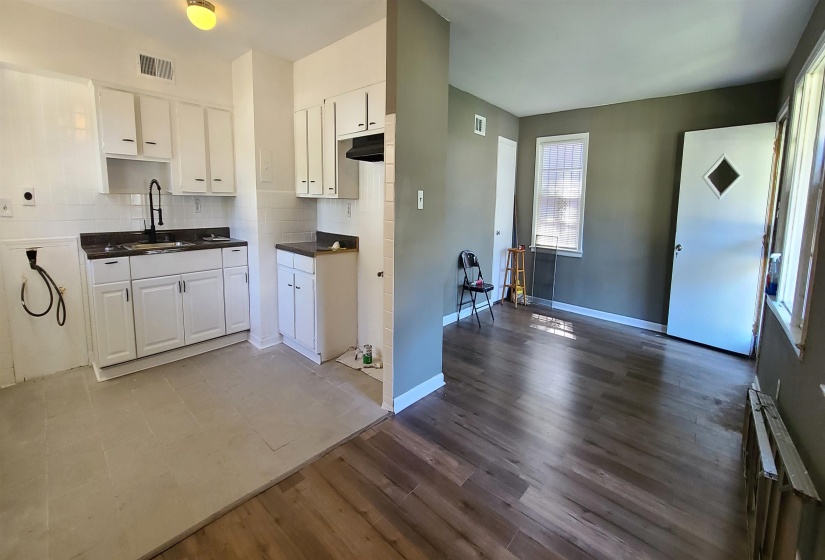 Kitchen featuring light wood-type flooring, sink, white cabinetry, radiator, and backsplash
