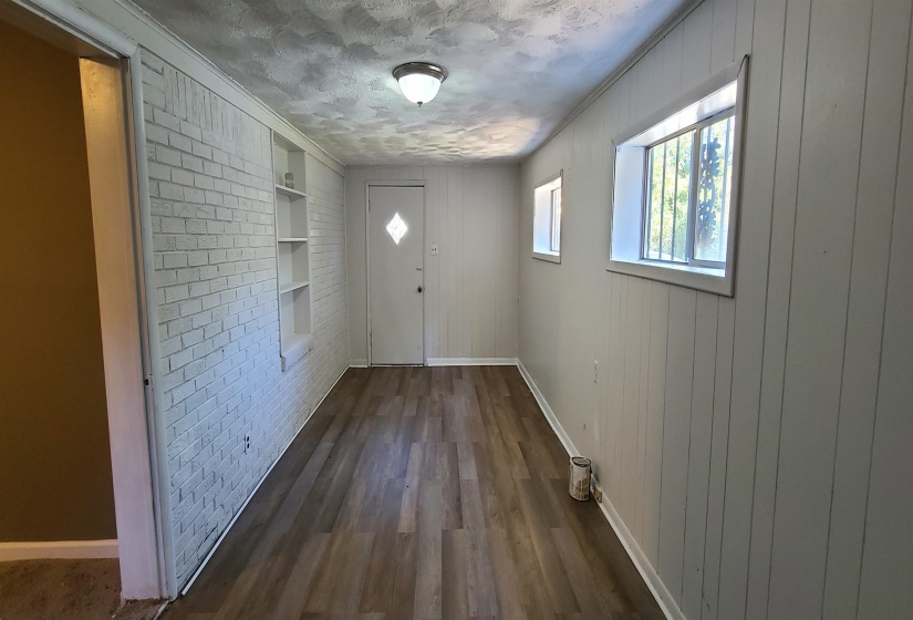 Entryway with brick wall, wood walls, dark hardwood / wood-style flooring, a textured ceiling, and ornamental molding