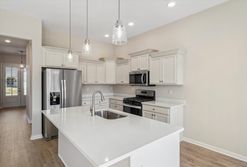 Kitchen featuring stainless steel appliances, white cabinets, an island with sink, and light wood-type flooring
