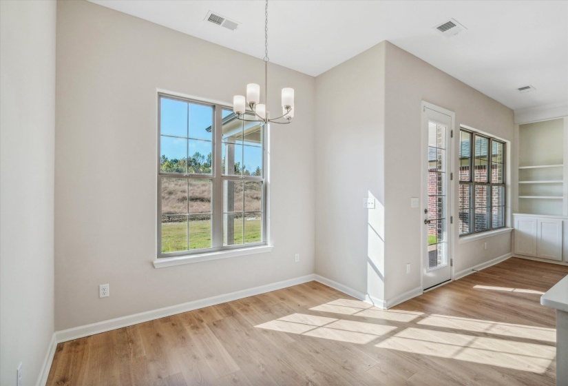 Unfurnished dining area with suspended lighting, built in shelves, light wood finished floors, and healthy amount of natural light