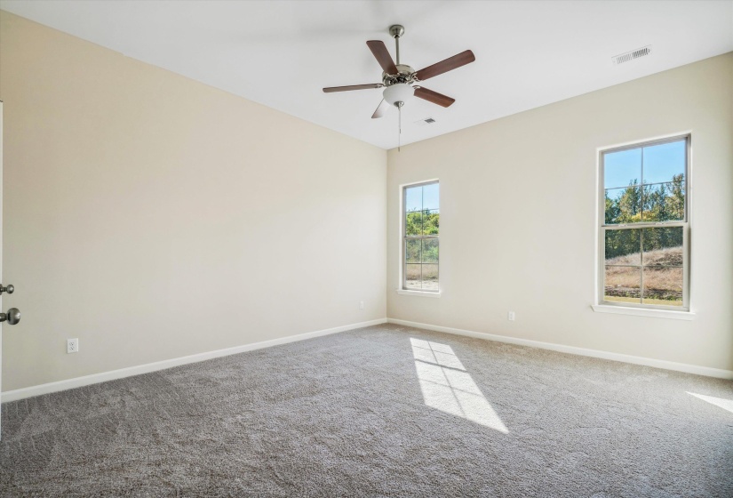 Carpeted empty room with baseboards and a ceiling fan