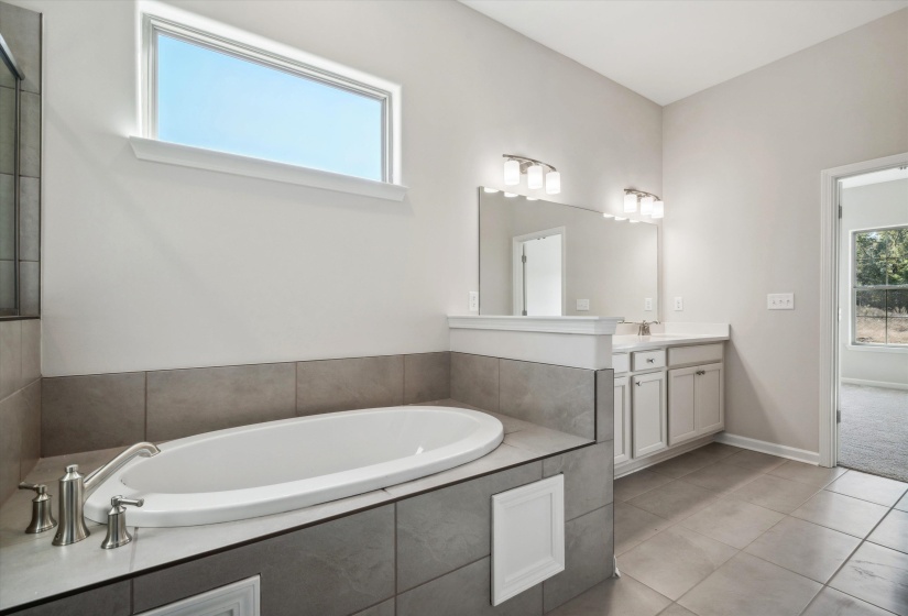 Full bathroom featuring vanity, plenty of natural light, a garden tub, and light tile patterned floors