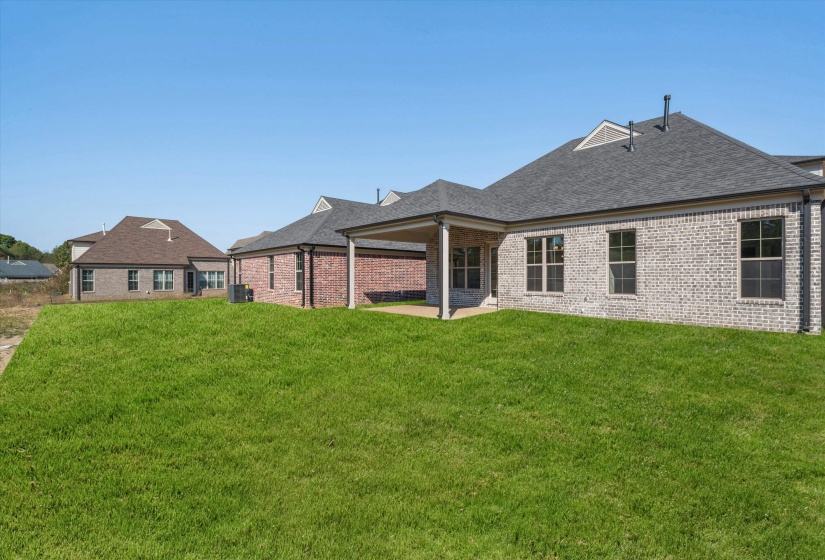 Rear view of house with a yard, a patio, brick siding, and roof with shingles