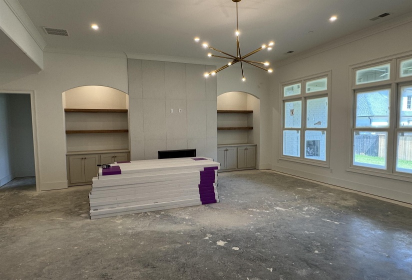 Spacious interior featuring a modern linear chandelier, recessed lighting, and a prominent fireplace wall