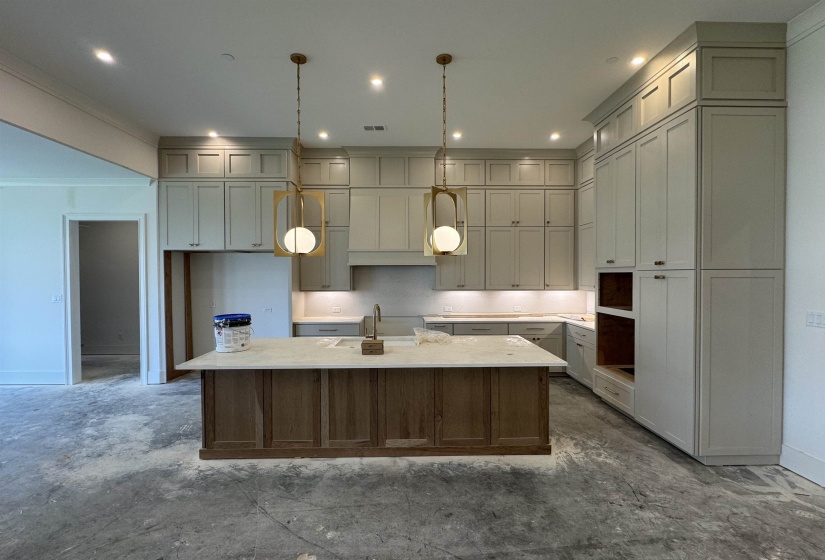 Contemporary kitchen featuring a two-toned island with a light-toned countertop, custom cabinetry extending to the ceiling, under-cabinet lighting, and modern pendant fixtures