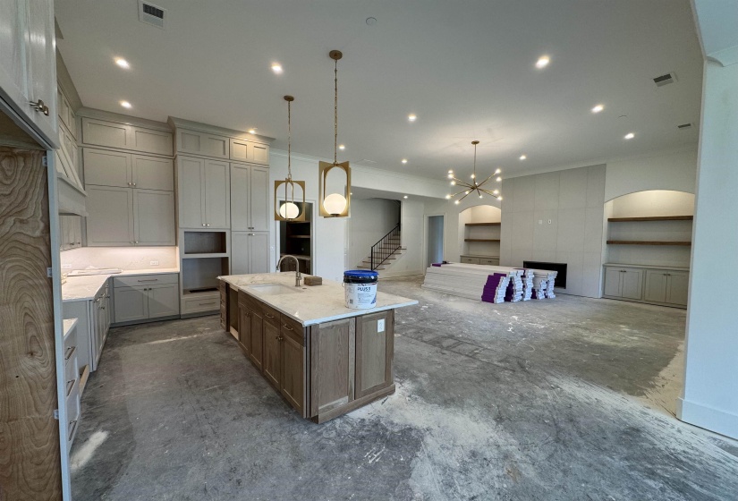 Open-concept living space featuring a kitchen with a large central island, light-toned cabinetry, and pendant lighting