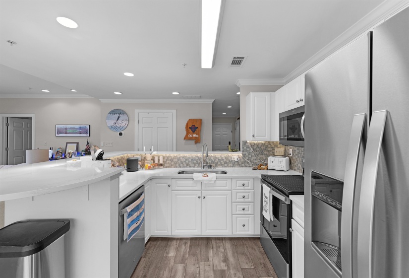 Kitchen with stainless steel appliances, crown molding, white cabinetry, a peninsula, and a kitchen breakfast bar