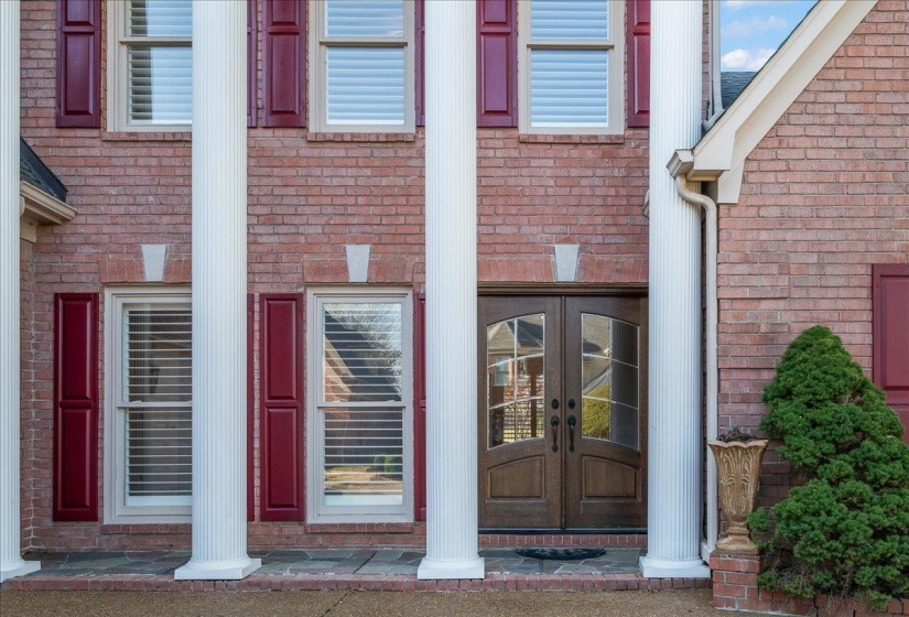Doorway to property featuring brick siding and a porch