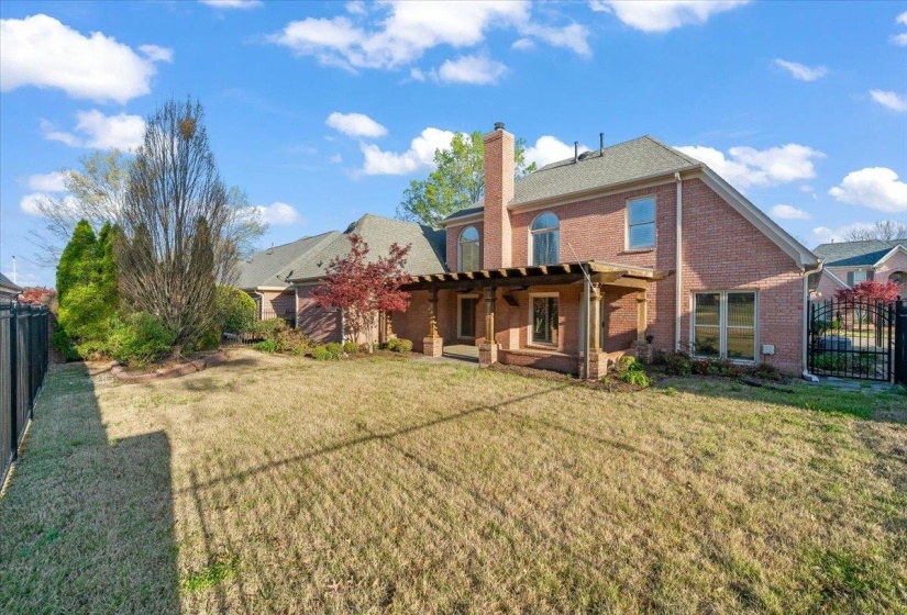 Back of property featuring a fenced backyard, brick siding, a chimney, a pergola, and a patio area