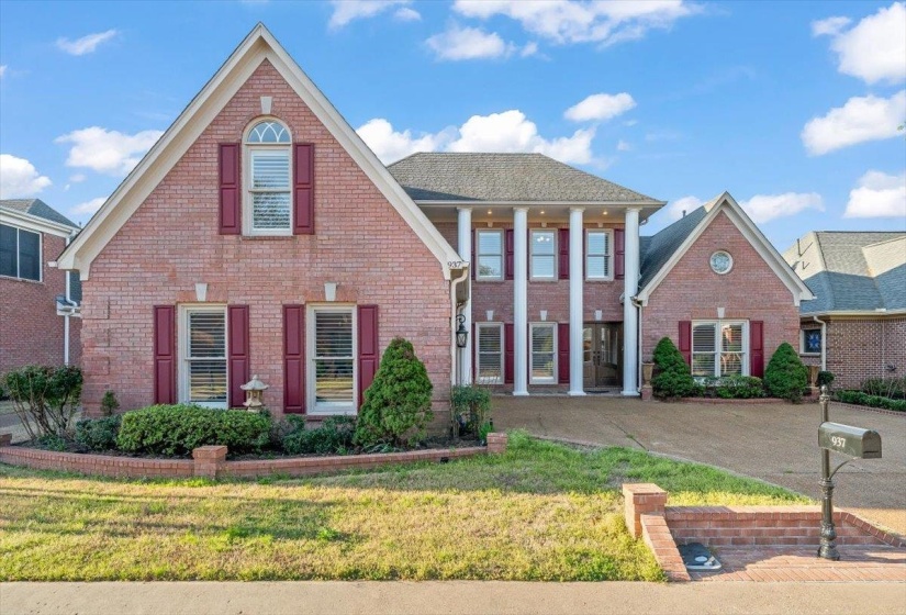 View of front of home featuring a front lawn, brick siding, and covered porch