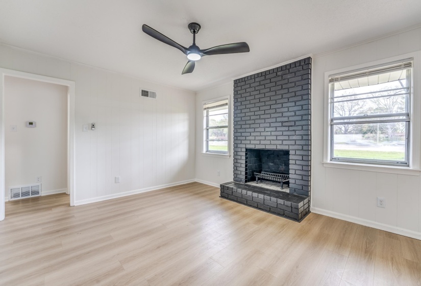 Unfurnished living room with ceiling fan, light wood-style flooring, a fireplace, and wood walls